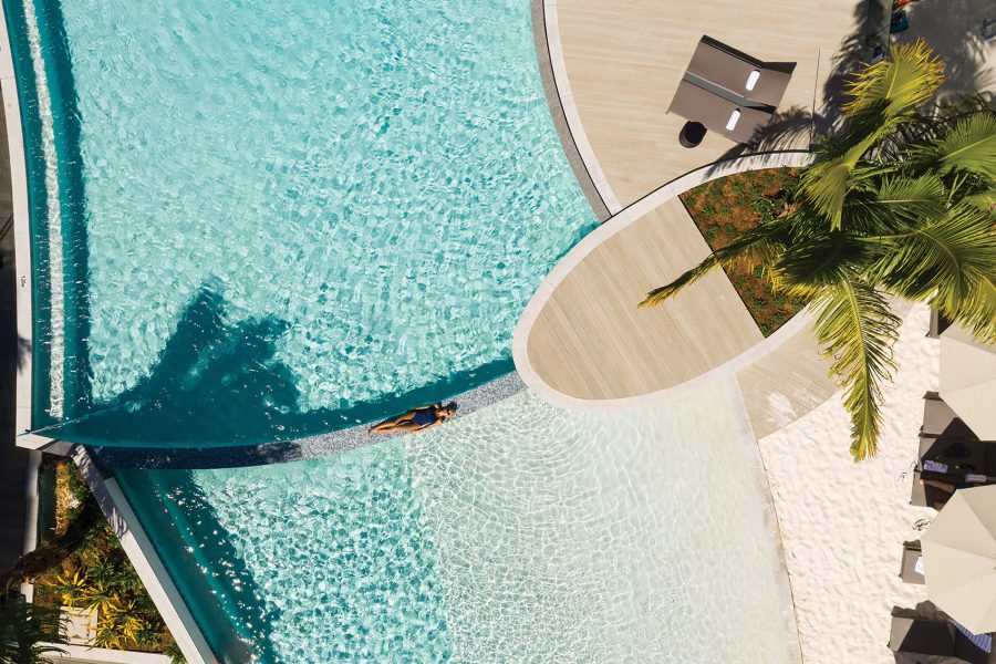 A woman relaxing at Cairns hotel Crystalbrook Riley’s hotel pool.   HED: The best hotels in Cairns for every type of traveller.