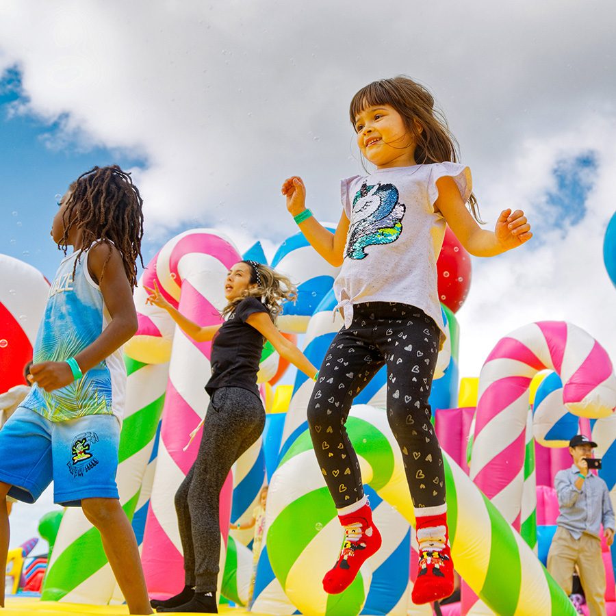 Children bouncing on a bouncy castle covered in inflatable candles and candy canes.