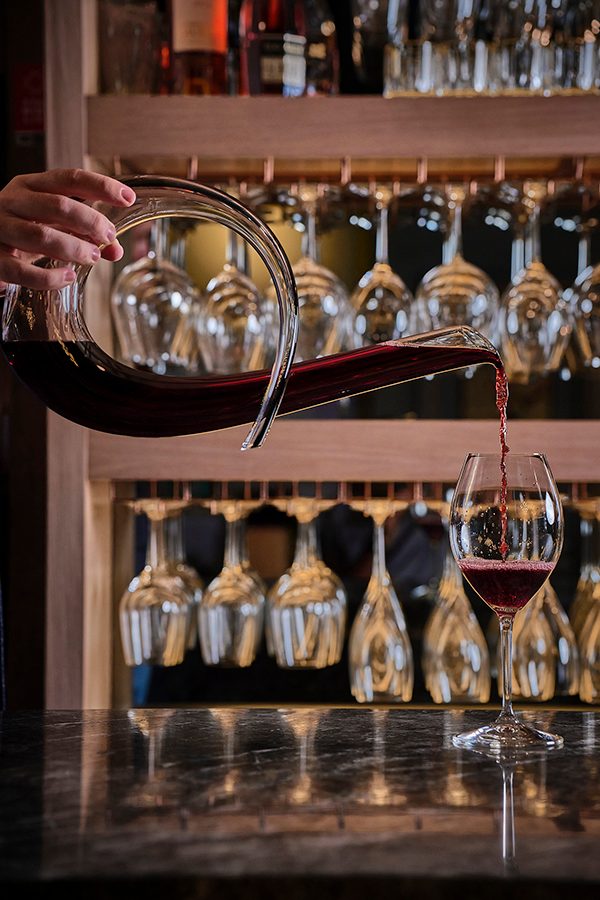 Shot of person pouring red wine from a decanter at Think Wine.