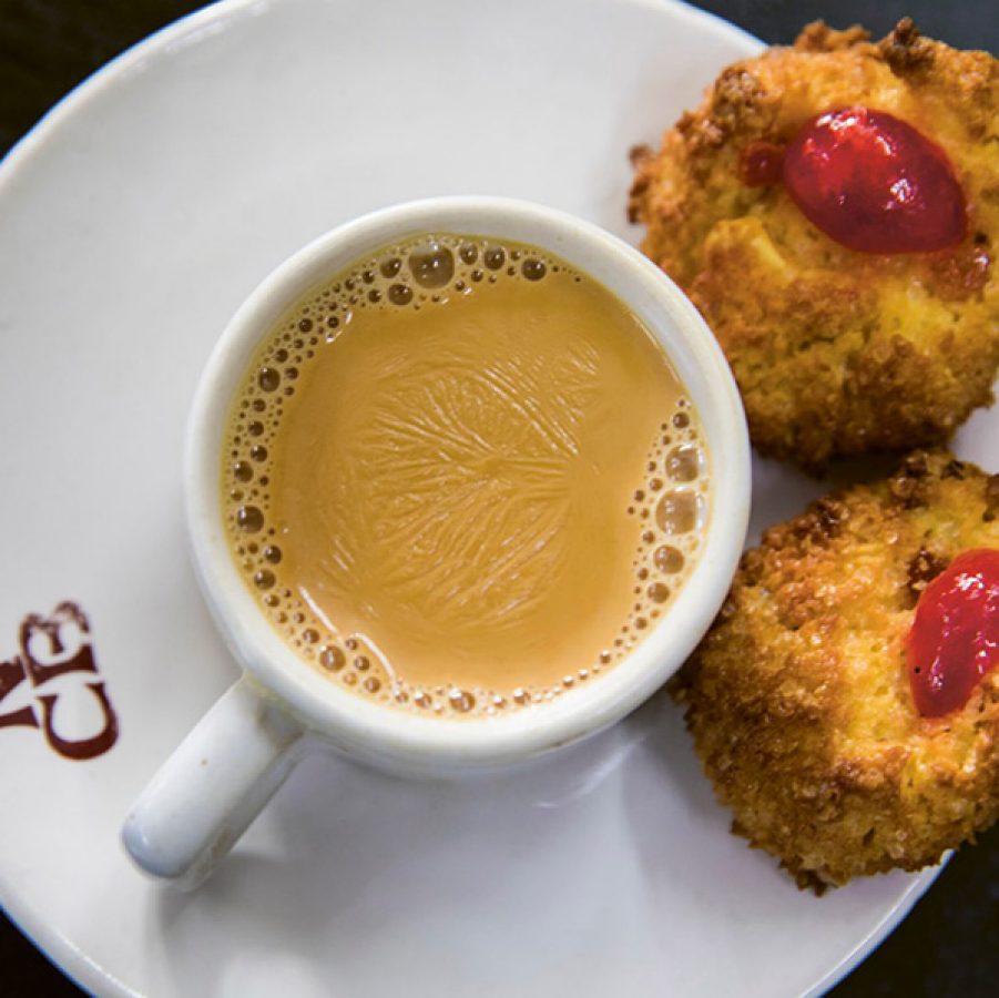 A topdown view of a cup of Irani chai served with two pieces of Osmania biscuits at Nimrah Cafe & Bakery in Hyderabad, India.