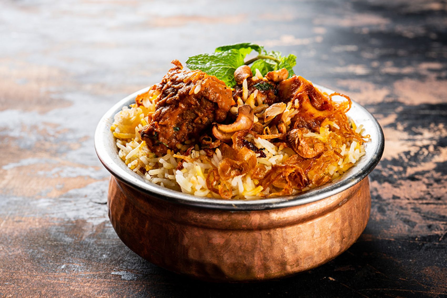 A closeup of a bronze bowl of biryani served at Shadab in Hyderabad, India.
