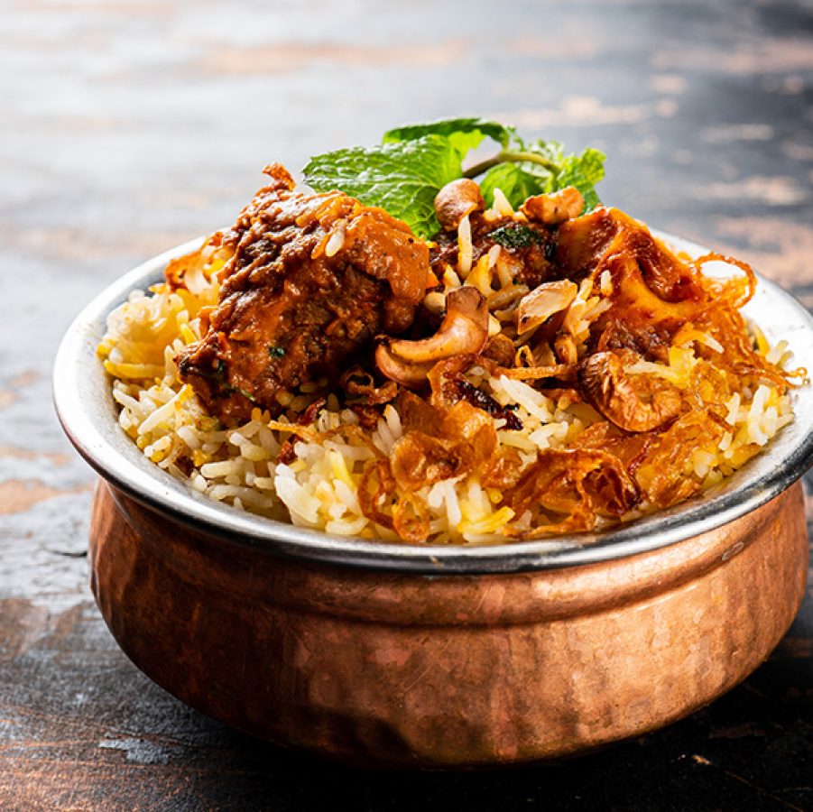 A closeup of a bronze bowl of biryani served at Shadab in Hyderabad, India.