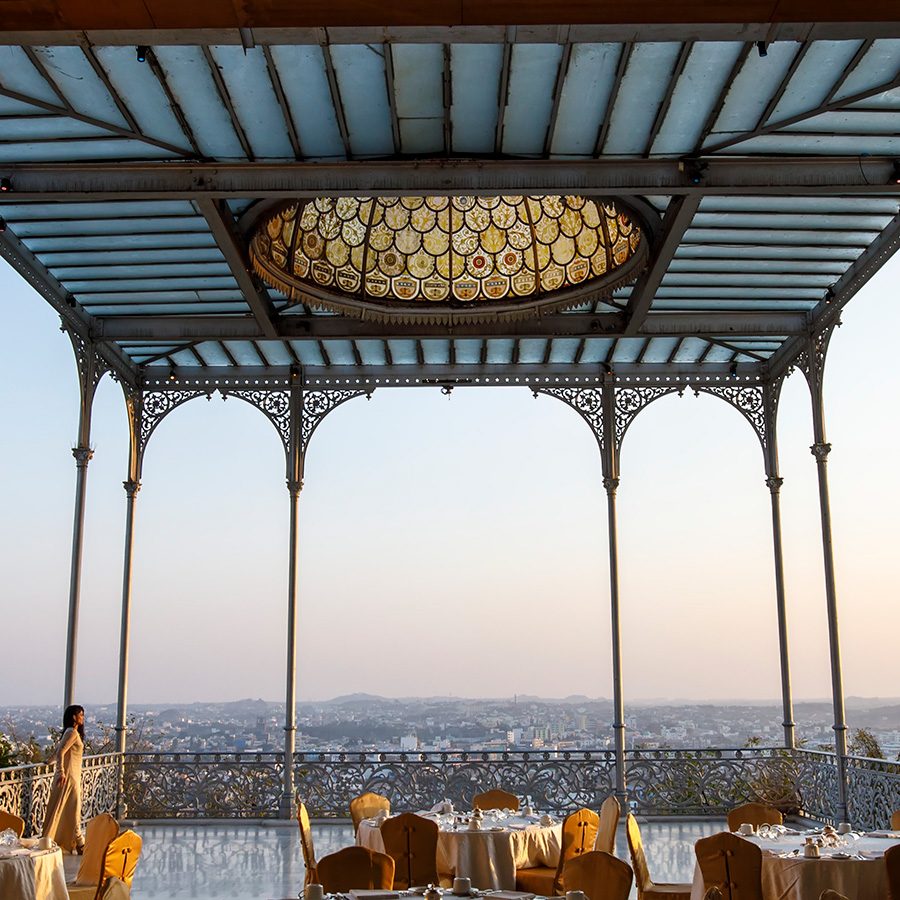 Inside Taj Falaknuma Palace with a panoramic city view of Hyderabad at dusk.