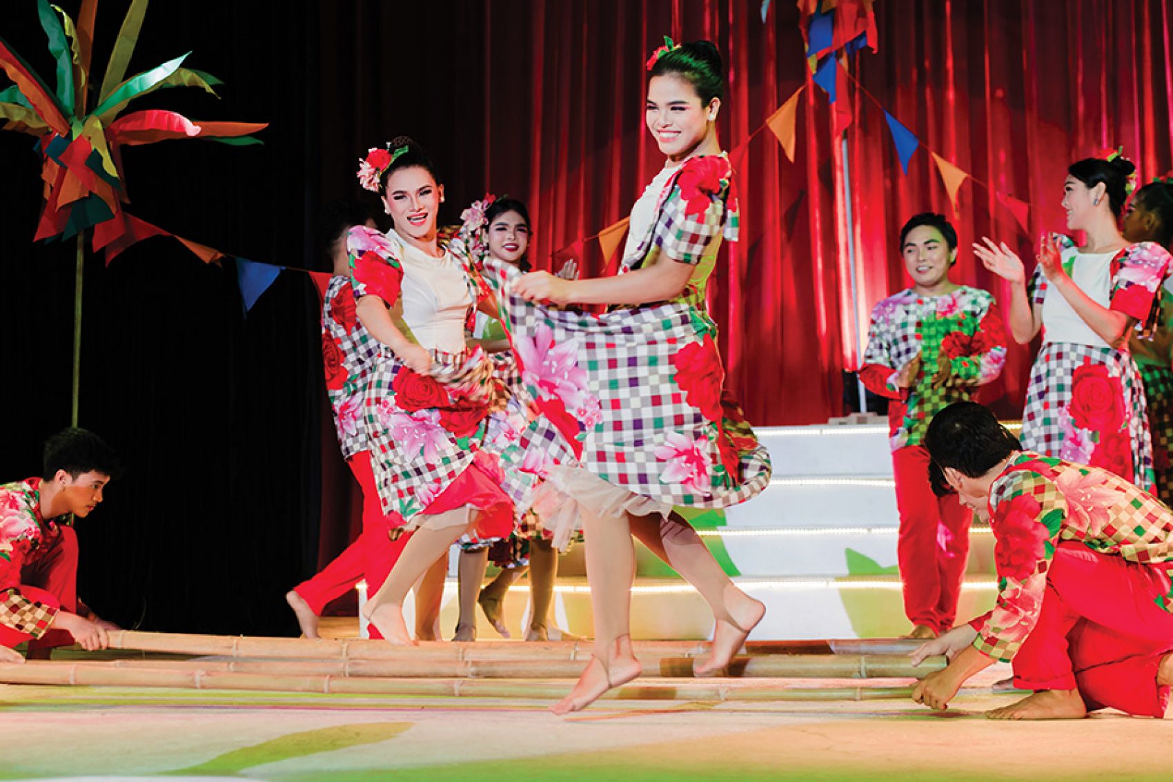 Tinikling dancers in red patterned dresses onstage at the White Note Pavilion.