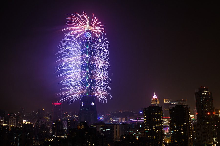 A view of Taipei 101 with a colourful display of fireworks shooting out from all sides of the tower at night.