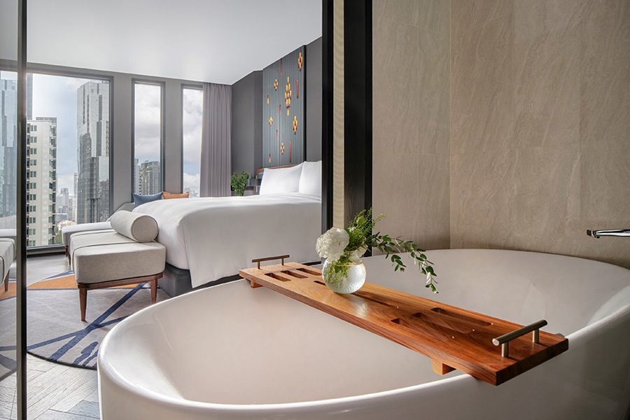An interior view of a premium room at InterContinental Bangkok Sukhumvit, featuring elegant designs, premium furnishings, a soaking bathtub, and floor-to-ceiling windows with city views. 