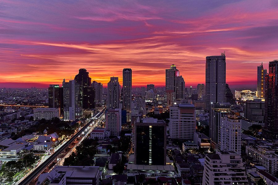 An aerial view of Bangkok city at sunset, the sky in pink, purple and orange gradient.