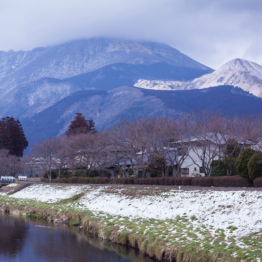 A landscape view of a snowy mountain and village next to a river in Yufuin, a day trip from Fukuoka.