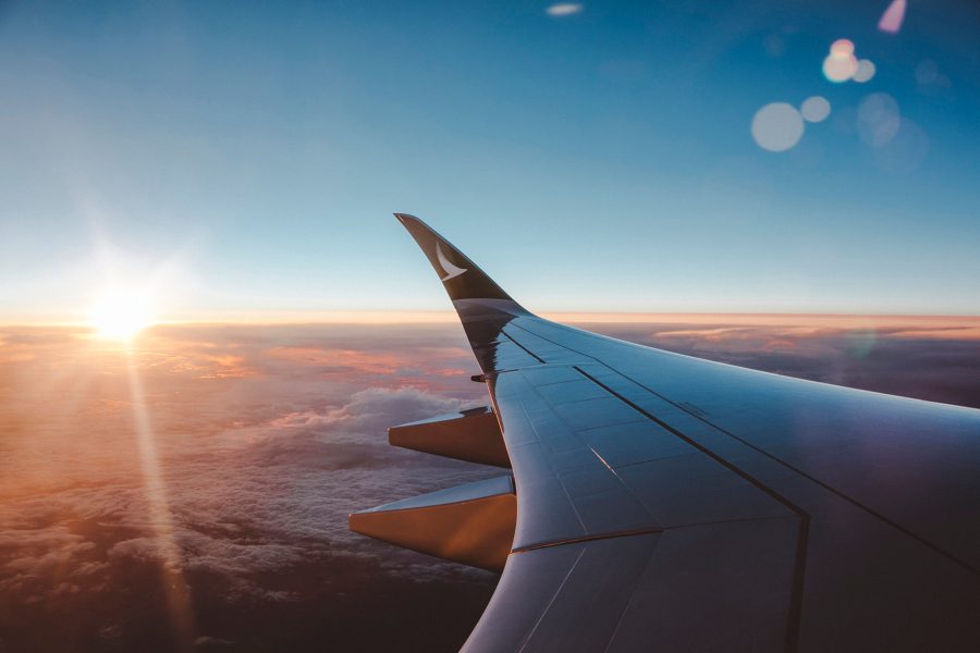 An aircraft wing with the Cathay logo flying over clouds at dawn.