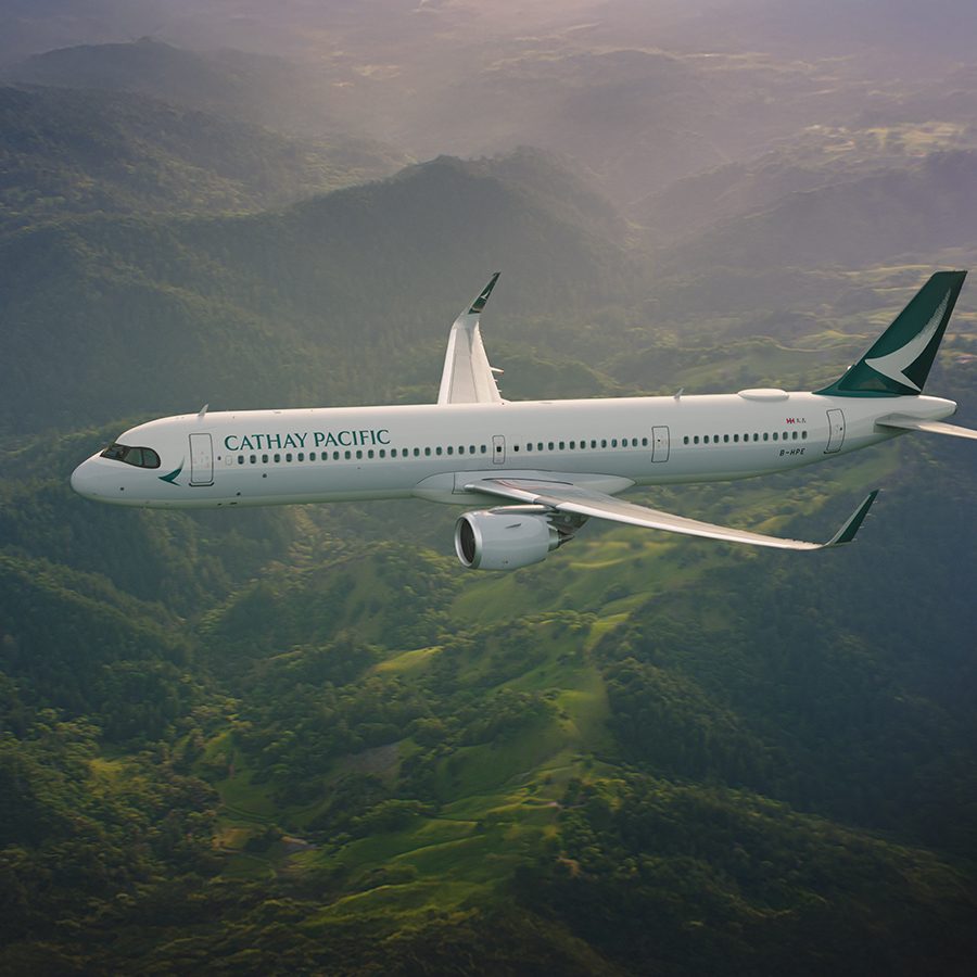 A Cathay Pacific aircraft flying over mountainous terrain in the daytime. 