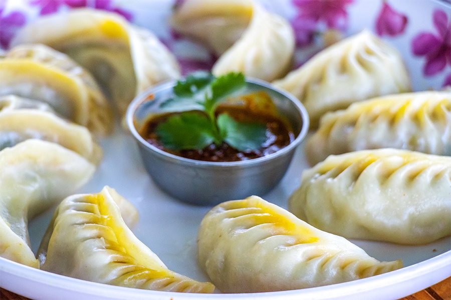 A plate of Nepali momo with a red dip in the middle.