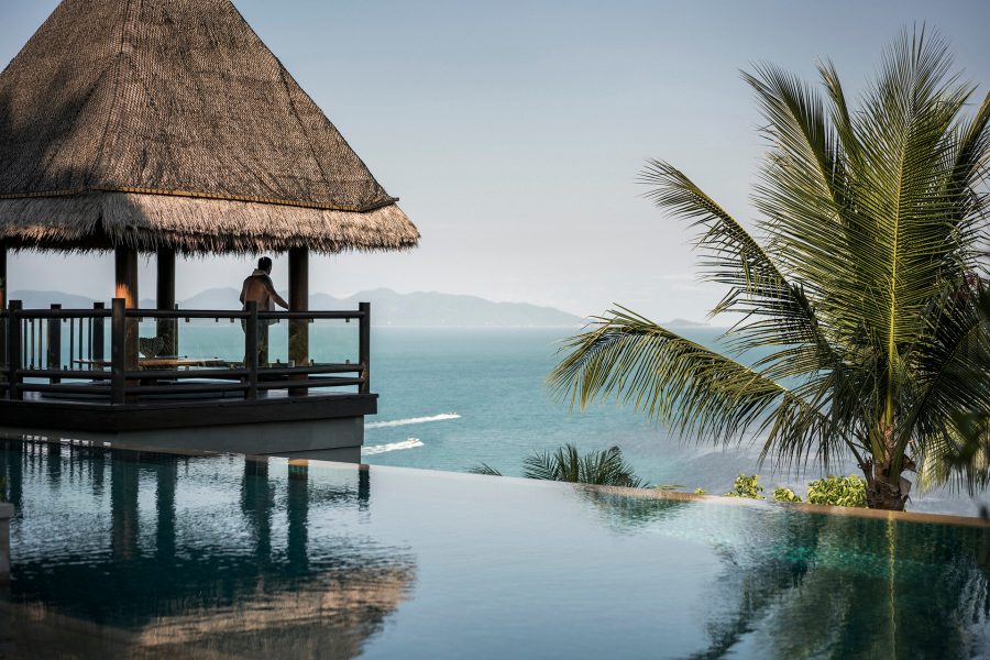 An outdoor hut perches on the edge of an infinity pool at Four Seasons in Koh Samui and looks out at the wide turquoise sea in the daytime. 