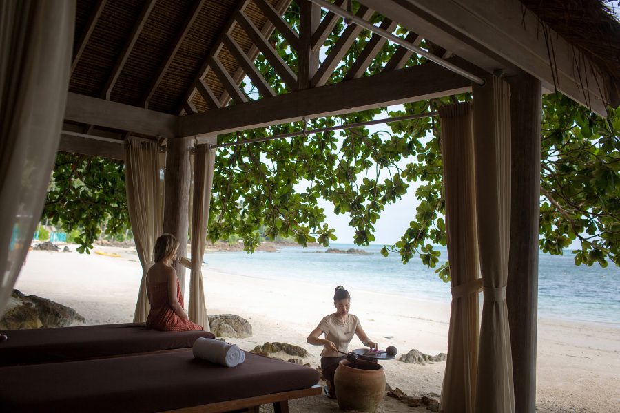 A staff member at Four Seasons prepares for a guest’s spa treatment in an outdoor hut on the beach at Koh Samui. 