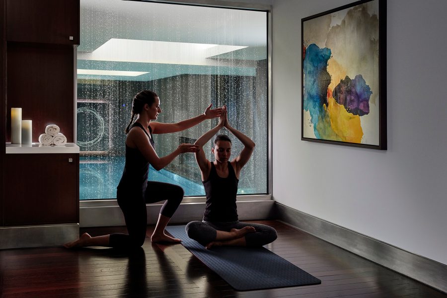 A woman practices yoga in a room as the instructor guides the movement of her arms at Mandarin Oriental Hyde Park in London. 