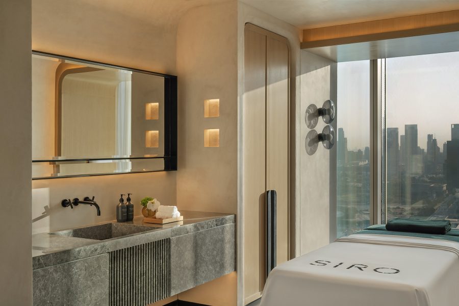 Interior of a spa treatment room at Siro One Za’abeel, which includes a bed and a sink, and looks out at the cityline.