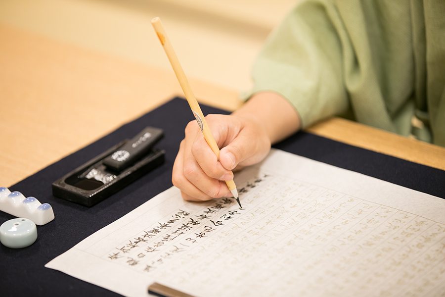 Person writing calligraphy in WaQoo Shitaderamachi in Osaka.