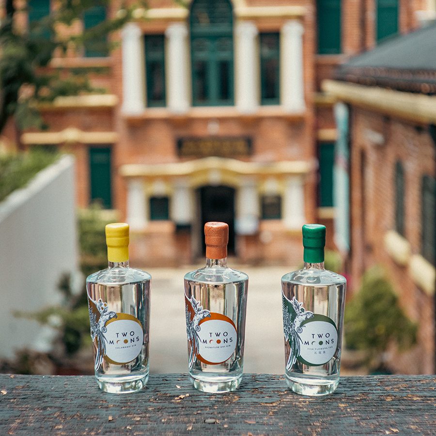 Three bottles of gin from Two Moons Distillery positioned on a staircase.  