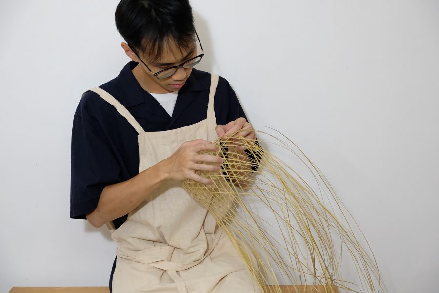 A man in an apron weaving a basket.