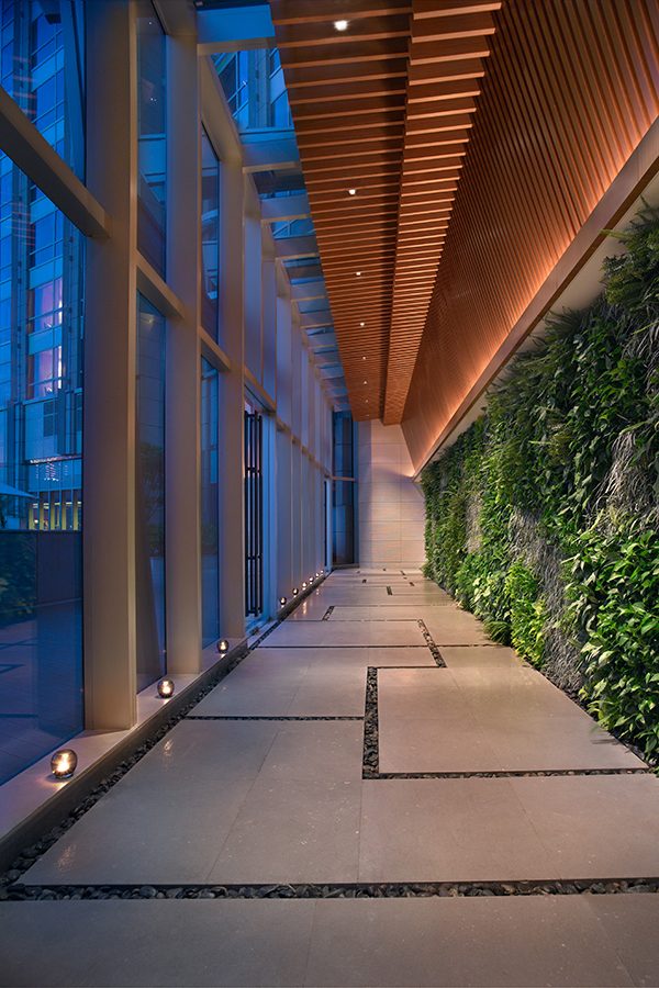 Floor-to-ceiling windows and green foliage line the indoor pathway to the Shui Xiang Spa at Grand Hyatt Shenzhen hotel in China.
