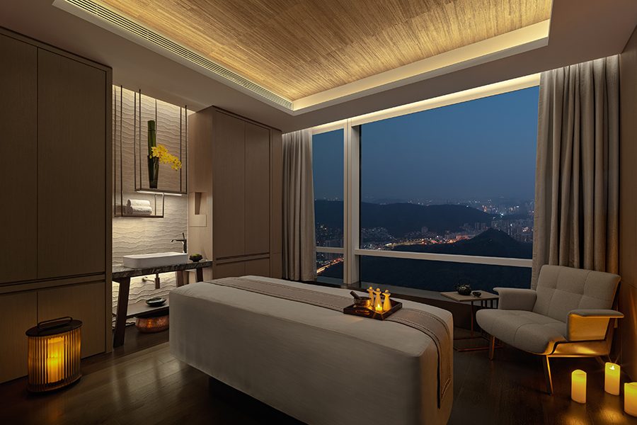A view inside a treatment room with a view of the city in the evening at the Mandarin Oriental Shenzhen spa.