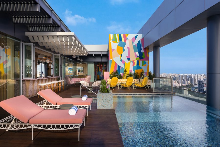Beach lounge chairs and retro artwork surround an outdoor pool at Las Palmas.