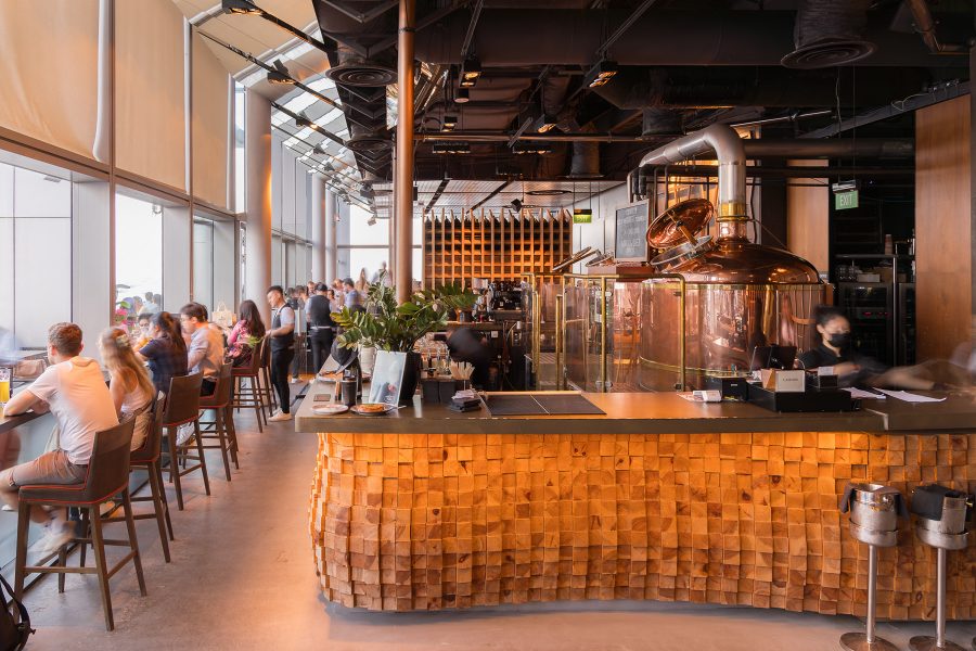  The interior of LeVeL33 houses craft beer brewing equipment behind a bar as diners seated around the perimeter of the bar look out the windows at the panoramic view. 