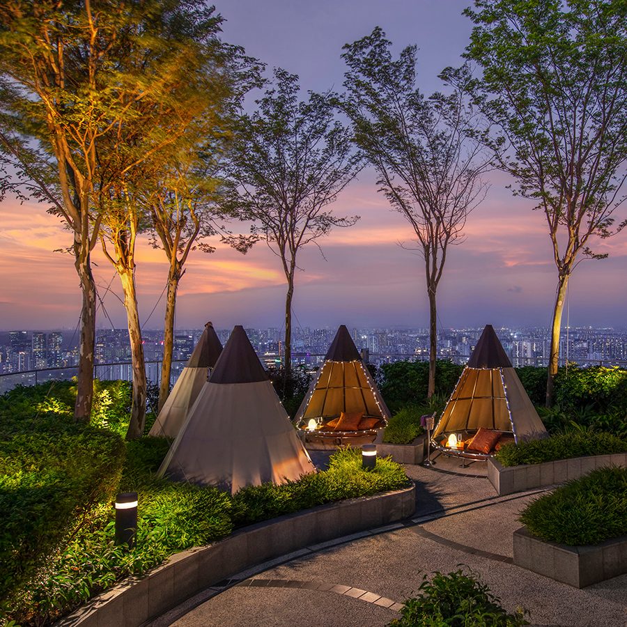Private seating in teepees are arranged across Mr. Stork’s rooftop garden bar, overlooking Singapore in the evening.