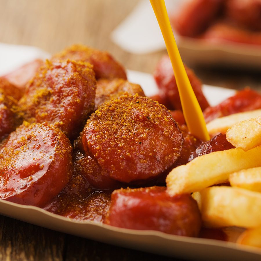 A serving of currywurst, German comfort food you can try at Bergwolf in Munich, is placed on the table. 