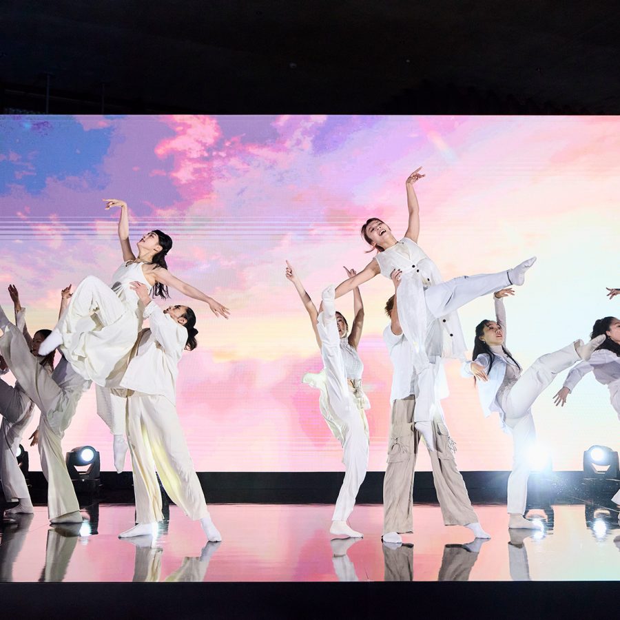 Dancers in white costumes performing in front of a pink and purple backdrop at The Diamond Drinks in Hong Kong.
