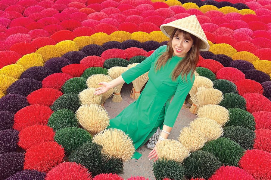 Cherry Yip knelt down surrounded by colourful incense at Quang Phu Cau Incense village, Hanoi.