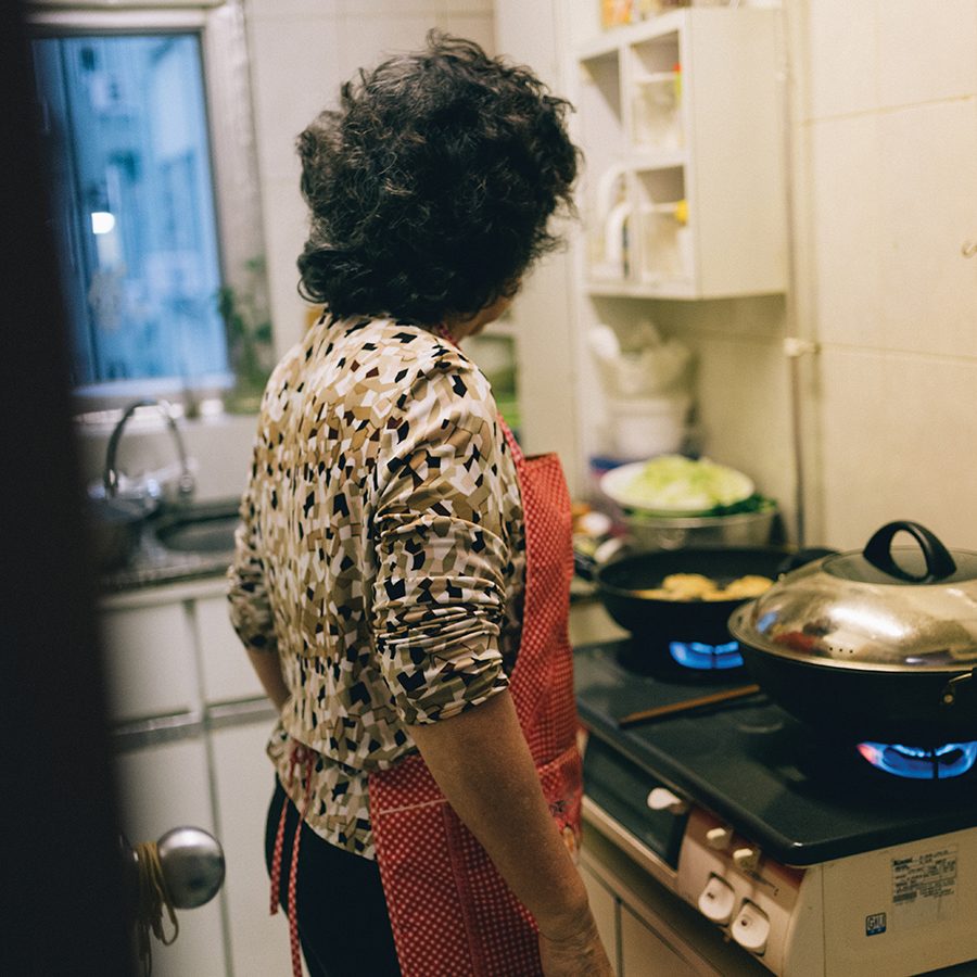 View of Sarah Köhler’s grandmother preparing food in the kitchen.
