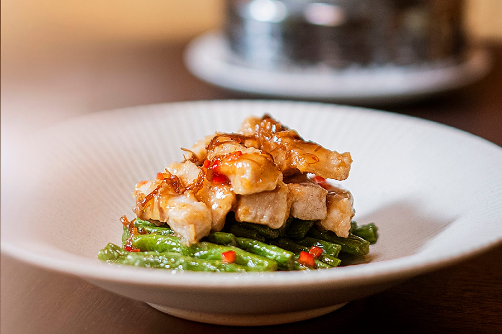 A close-up of a white dish of stir-fry meat and vegetables served at Michelin-starred Yat Tung Heen Chinese restaurant in Hong Kong.