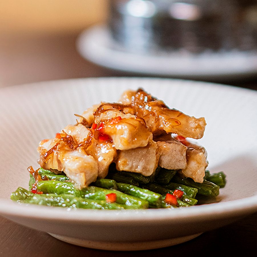 A close-up of a white dish of stir-fry meat and vegetables served at Michelin-starred Yat Tung Heen Chinese restaurant in Hong Kong.