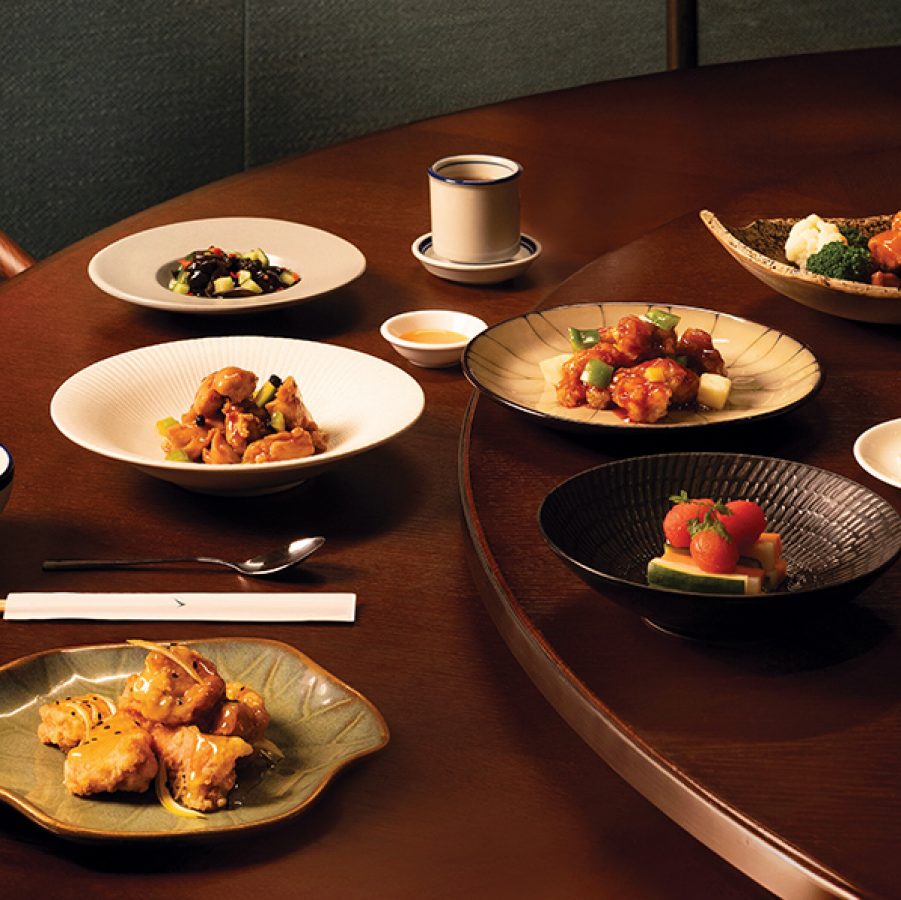 A group shot of classic Cantonese dishes on a round wooden table at Michelin-starred Yat Tung Heen Chinese restaurant in Hong Kong.