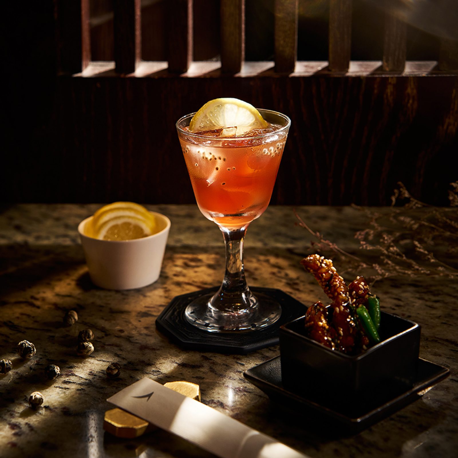 An orange-coloured cocktail and a dish of crispy shredded mushrooms with French beans by Mott 32 for Cathay. 