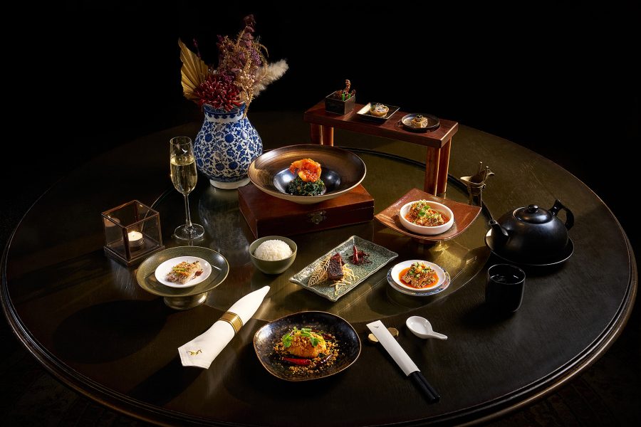 A table laden with dishes by Hong Kong’s Mott 32 for Cathay along with a vase, a teapot and a glass of champagne.