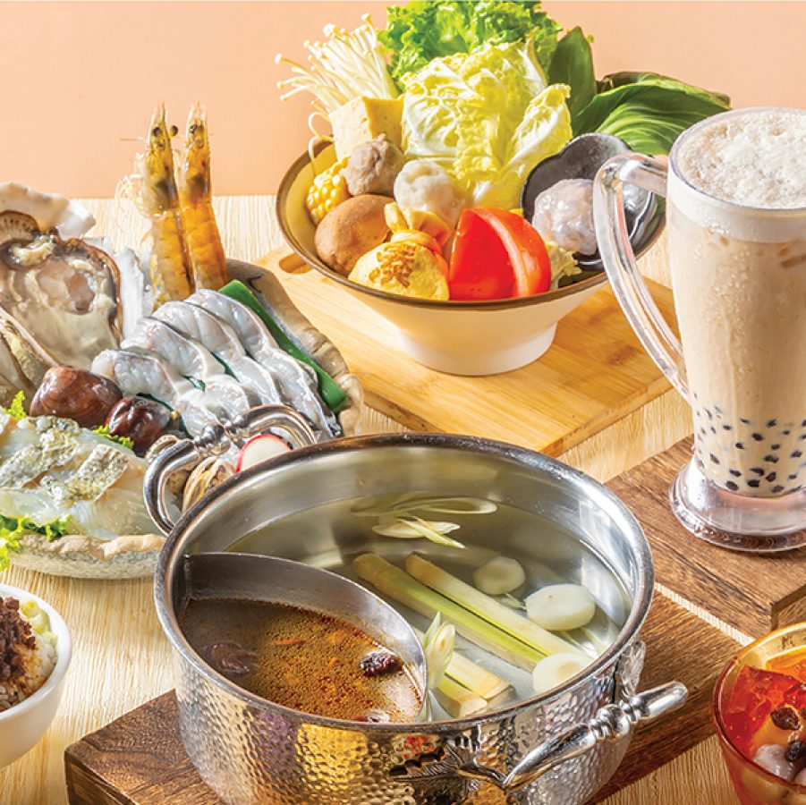 A group shot of various seafood, vegetable and meat hot pot dishes with two kinds of soup base and a glass of bubble milk tea, served at Xiabu Xiabu, Hong Kong.