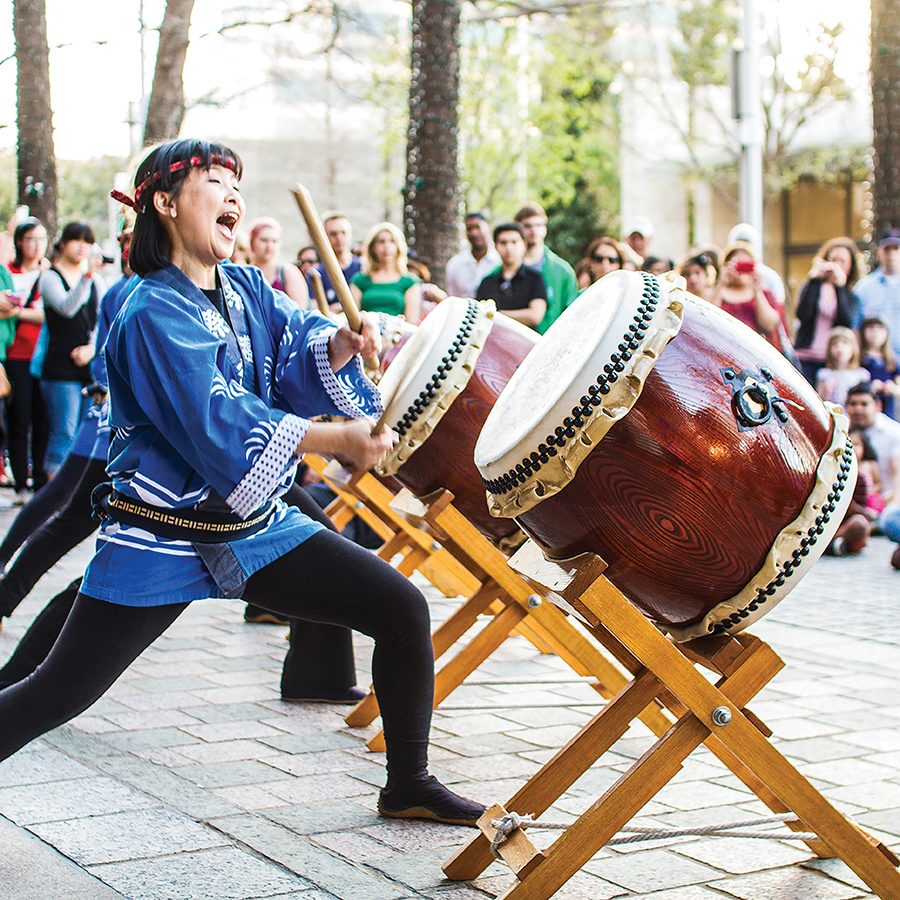 A woman banging on a wadaiko at a Japanese fall festival cultural and art performance on the street in Dallas.