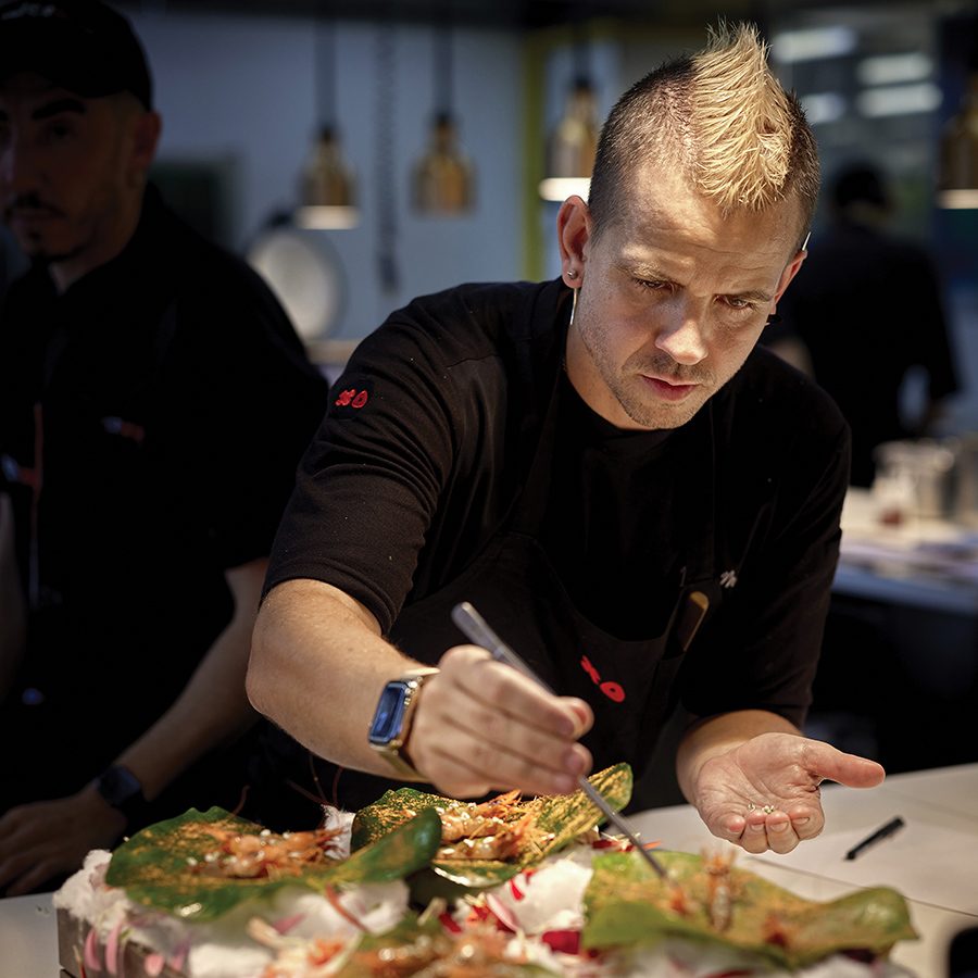 A portrait of chef Dabiz Muñoz plating a dish at DiverXO restaurant in Madrid.