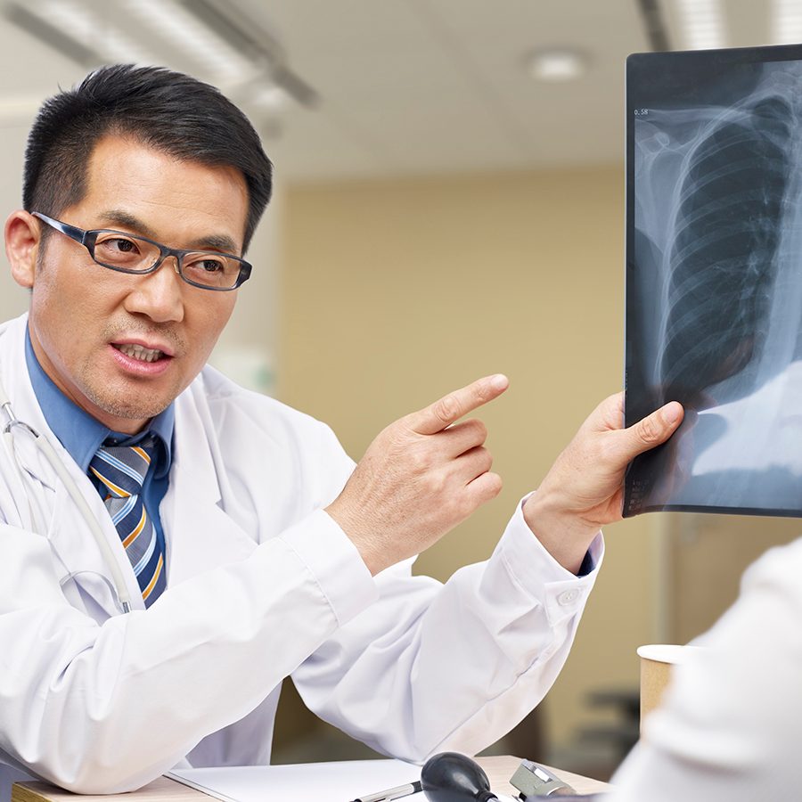 A doctor holds up an X-ray and explains the diagnosis to a patient at the hospital.