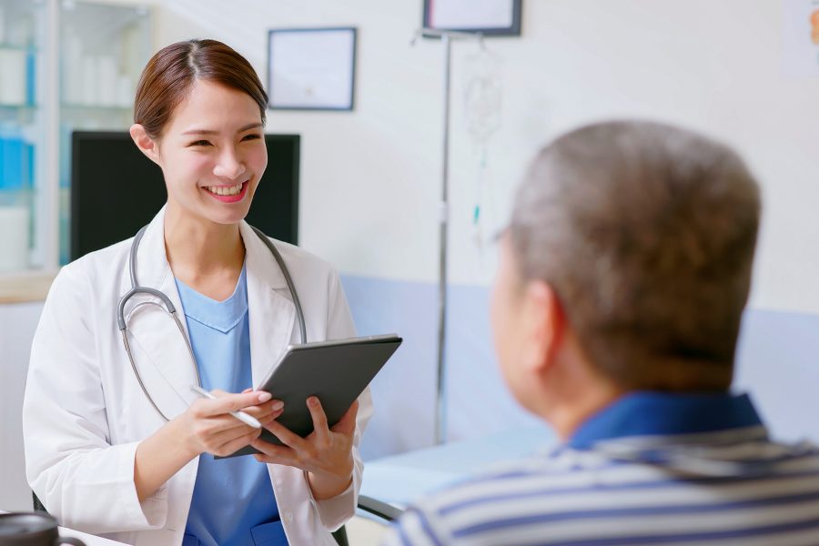 A doctor smiles at a male patient in a health clinic while providing medical services.