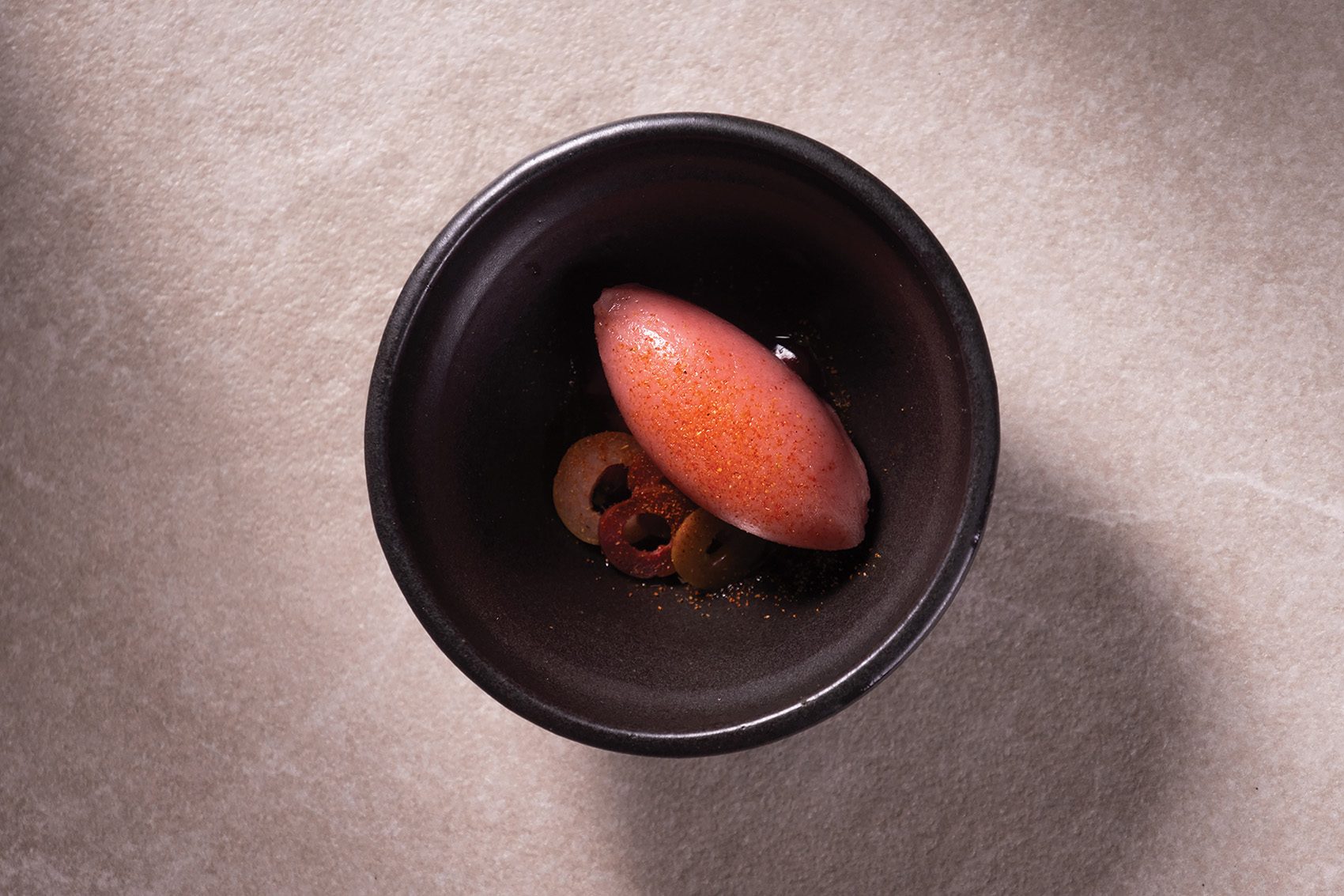 A close-up flat lay of a quenelle anardana karwanda ice cream served at fine dining Masque in Mumbai