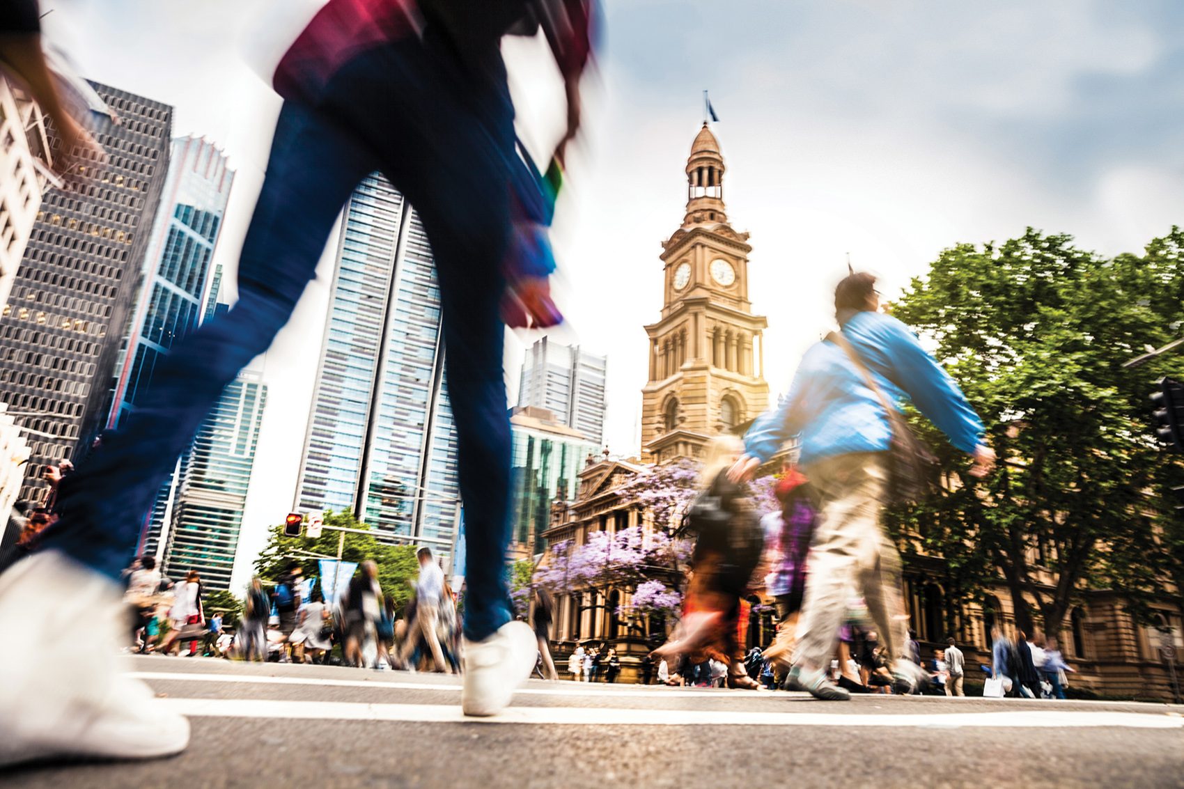 Low angle shot of people walking around the Sydney Town Hall Clock Tower.