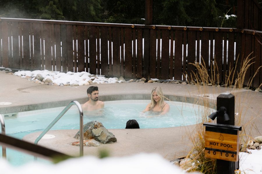 Three people relax in an outdoor pool at Scandinave Spa Whistler.