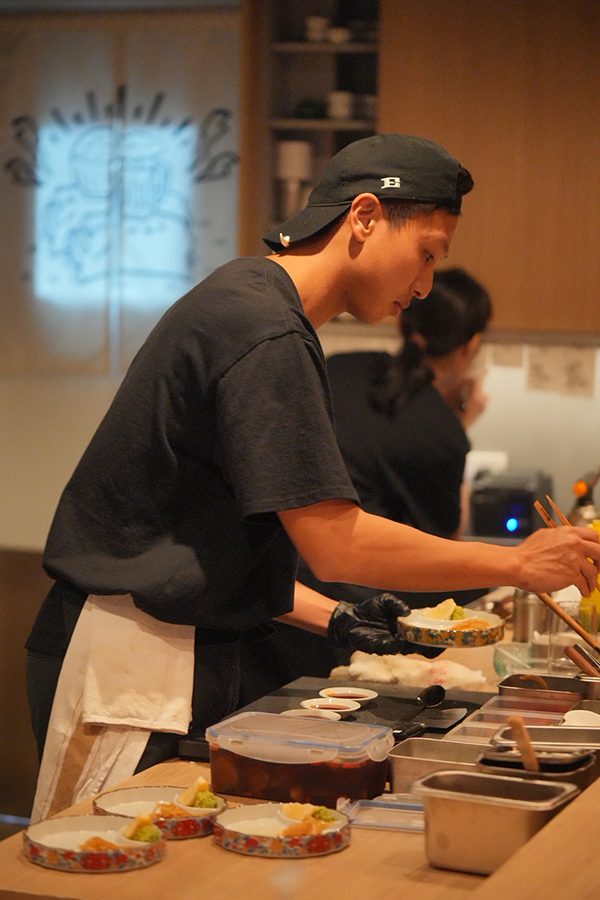 A chef at Inoshishi in Hong Kong prepares dishes behind the bar of the open kitchen.