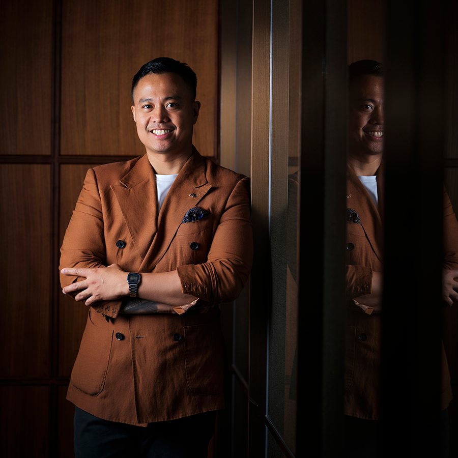 A portrait of Filipino-Hong Kong mixologist Joe Villanueva smiling in a brown suit at Jin Bo Law.