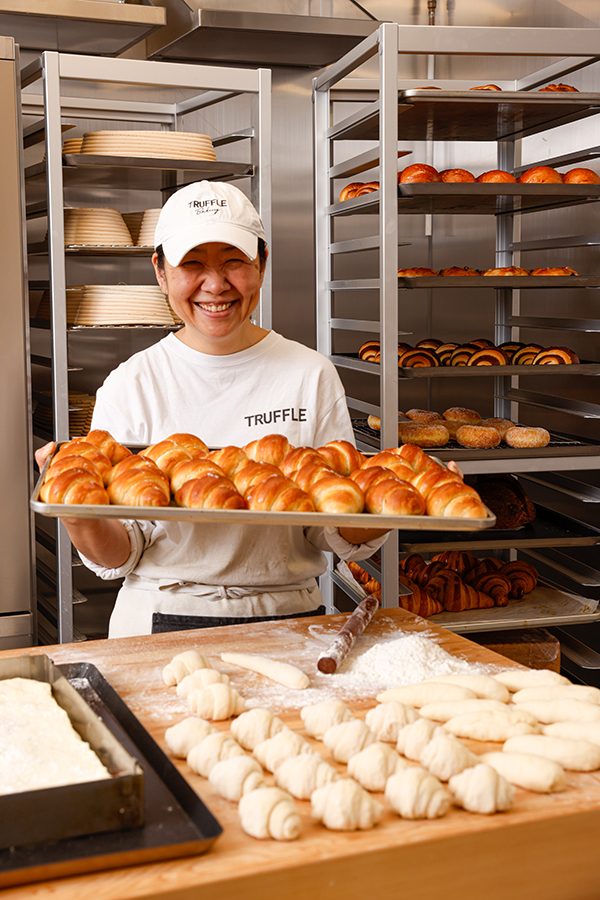 Chef baker Komata Naoko smiling while holding a tray of croissant inside Truffle Bakery in Hong Kong.