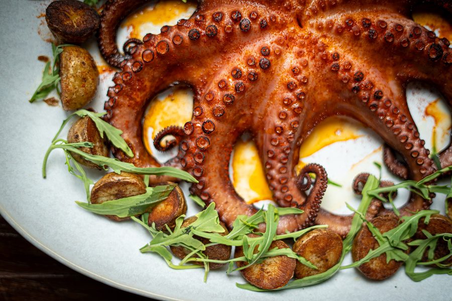 A cooked octopus on a plate with potatoes and rocket served at Boca, Dubai. 
