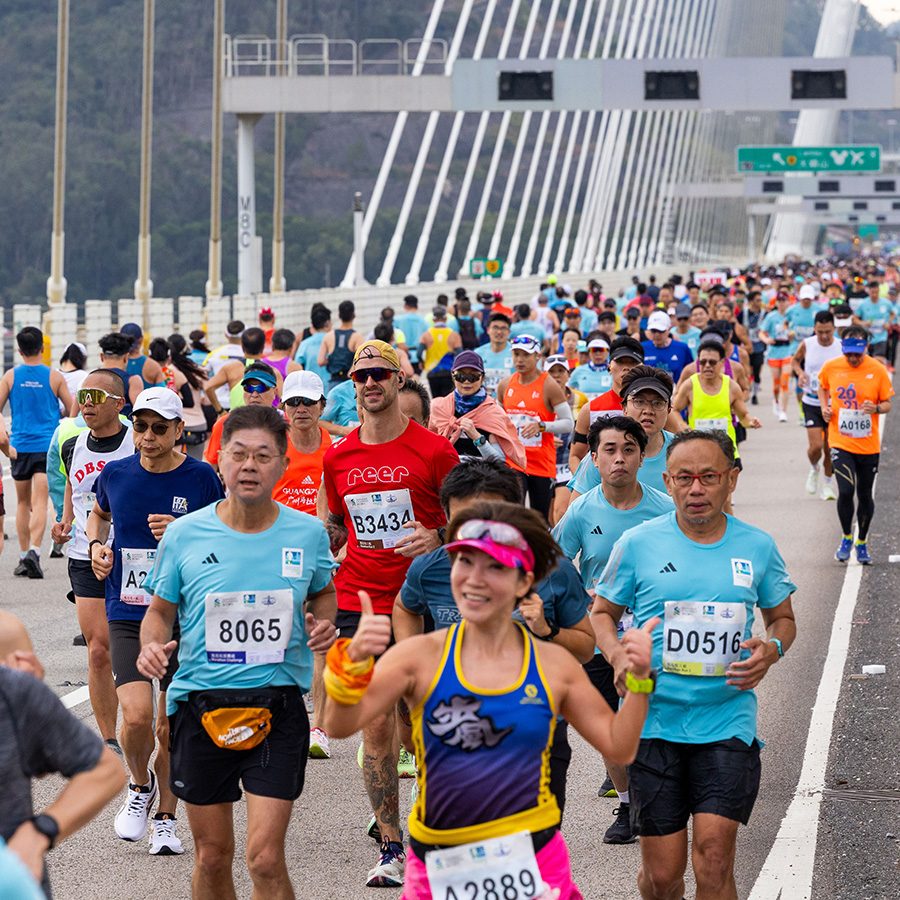A crowd of Standard Chartered marathon runners running on the Tsing Ma Bridge during daytime