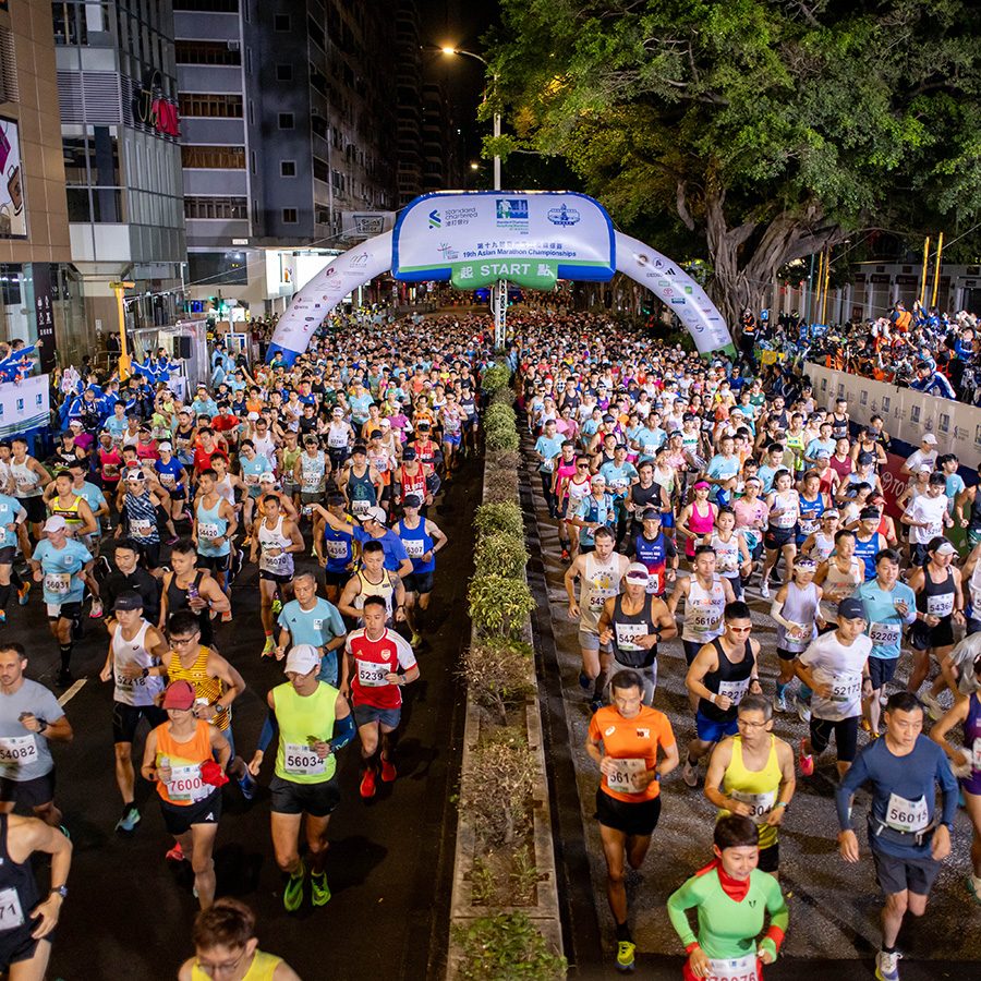 A wide shot of a crowd of runners at a Standard Chartered Bank Marathon in Hong Kong at night